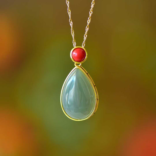 Close-up of water drop shaped Hetian jade pendant with cinnabar accent in sterling silver"