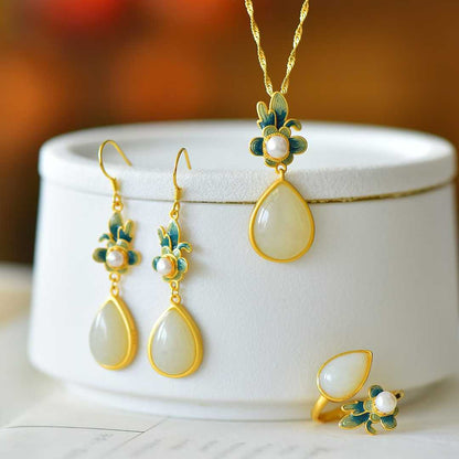 Close-up of white Hetian nephrite teardrop with carved silver orchid motif in vintage setting